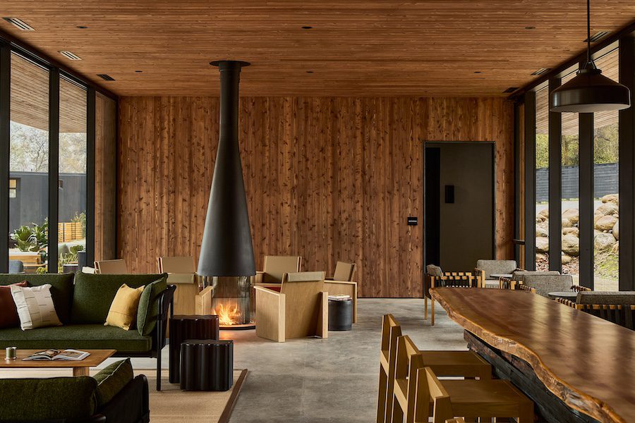 AutoCamp Sequoia Clubhouse Interior modern matte black fireplace raw edge communal wood table green sofa