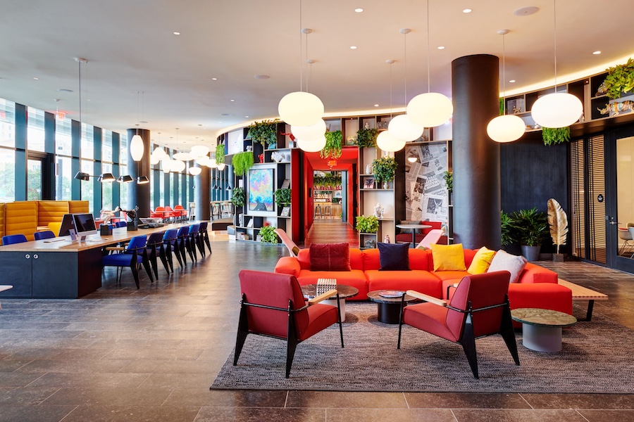 Miami World Center CitizenM globe pendant lights orange sectional sofa blue red chairs communal workspace table indoor plants